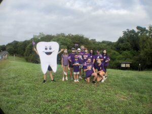 A group of dental professionals posing in front of a large tooth.