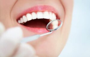 Close up of a woman's mouth during a dental examination with a magnifying glass.
