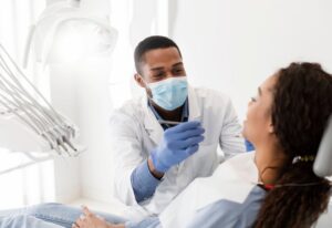 A man and a woman receiving dental care in a dentist's chair.